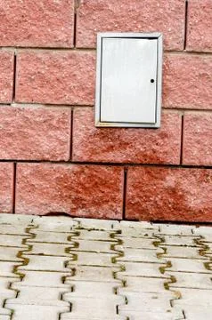 Sidewalk and wet red block wall with switchboard. Stock Photos