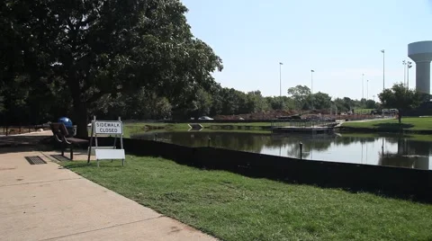 Sidewalk closed around pond at park. Stockbeeldmateriaal 66809404