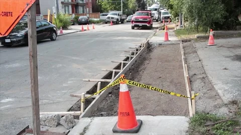 Sidewalk construction building dug out with wood frame and pylons caution tape Stock Footage 251357064