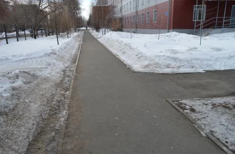 The sidewalk intersection in the Park, the snow on the roadside, spring Stock Photos