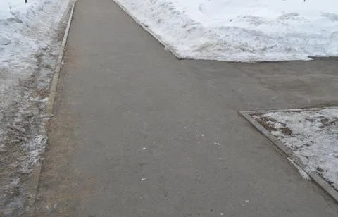 The sidewalk intersection in the Park, the snow on the roadside, spring Stock Photos