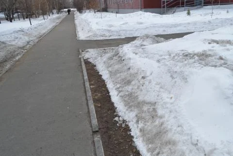 The sidewalk intersection in the Park, the snow on the roadside, spring Stock Photos