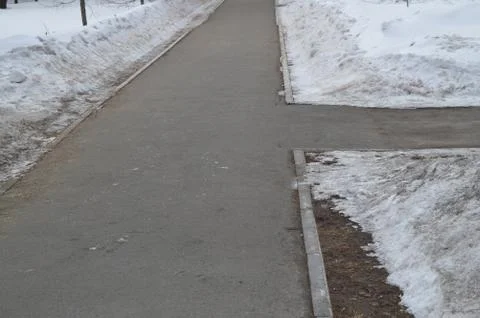 The sidewalk intersection in the Park, the snow on the roadside, spring Stock Photos