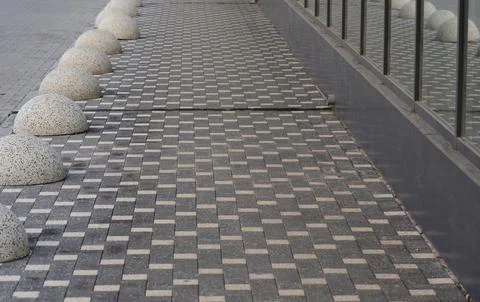 A sidewalk with a row of cement balls on it.  Stock Photos