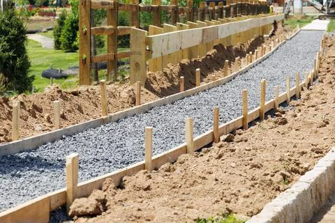 A sidewalk is under construction, a concrete curb is being installed and the  Stock Photos