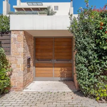 Sidewalk by upscale house entrance solid wooden door and foliage Stock Photos
