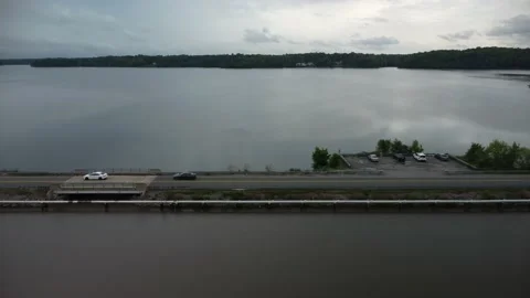 Sideward flight flight with road next to lake with stormy sky Stock Footage 239938947
