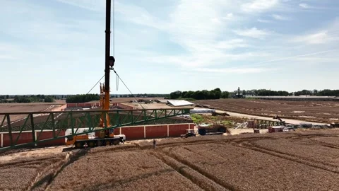 Sideway drone shot of mobile telescopic crane lifting large wooden roof truss Stock Footage 315242130