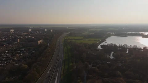 Sideways aerial view of highway traffic near Dutch town at sunset Stock Footage 335831973