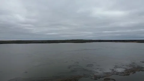 Sideways drone flight along a moody riverbank on an overcast day Stock Footage 312416573