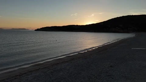 Sideways Drone Flight Along Tranquil Sunrise Beach with Sun Rising Behin 库存影片 334796628