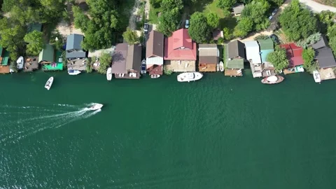 A sideways drone flight along a turquoise clear river with holiday homes and Stock Footage 284631483