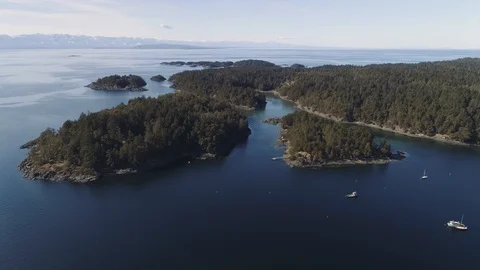 Sideways moving aerial shot with view of rocky islands and trees. Boats below. Video stock 104581522