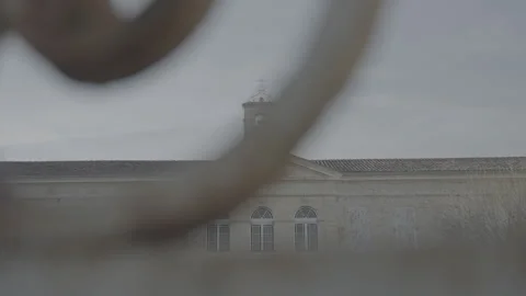 Sideways moving shot behind an iron fence filming the Hospital building in 库存影片 324693042