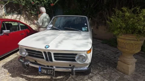 Sideways tracking shot of a BMW 2002 Touring at a classic car show in Attard Vidéo 323896961