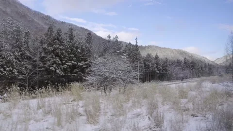 Sideways view out of train window passing through rural winter landscape in Stock Footage 327630771