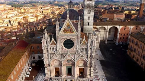 Siena Cathedral's stunning Gothic facade and Mangia Tower in Tuscany bathed in Stock Footage 296425194