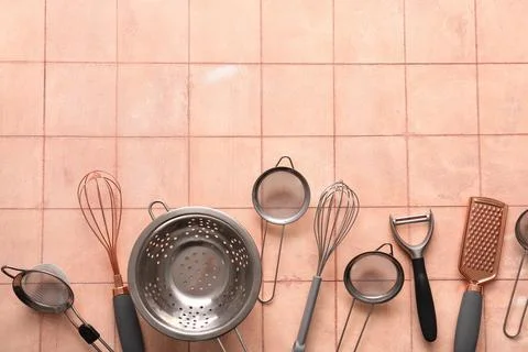 Sieves with colander and different kitchen utensils on pink tile background Stock Photos