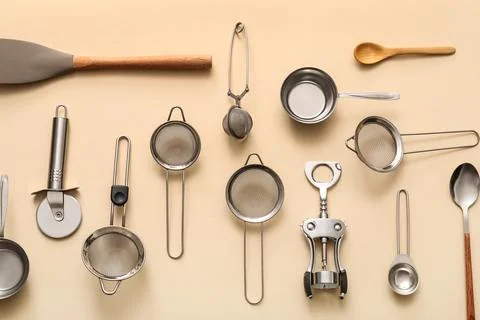 Sieves with different kitchen utensils on beige background Stock Photos