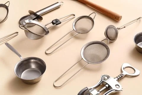 Sieves with different kitchen utensils on beige background Stock Photos