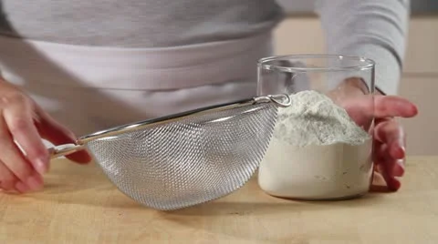 Sieving flour onto a worksurface Stock Footage 24663267