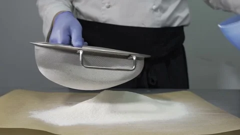 Sifting flour into bowl on table. Close up. The cook prepares Stockbeeldmateriaal 73805178
