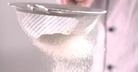 Sifting flour in a kitchen with fine mesh strainer for baking preparation Stock Footage 325088044