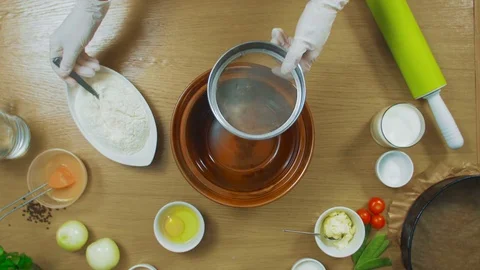 Sifting flour through sieve on wooden table, top view Stock Footage