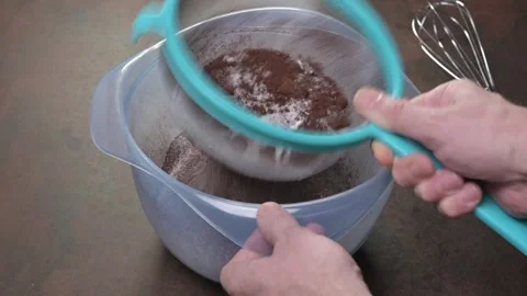 Sifting a mixture of white flour, sugar and cocoa powder. Male hand. Stock Footage 243859061