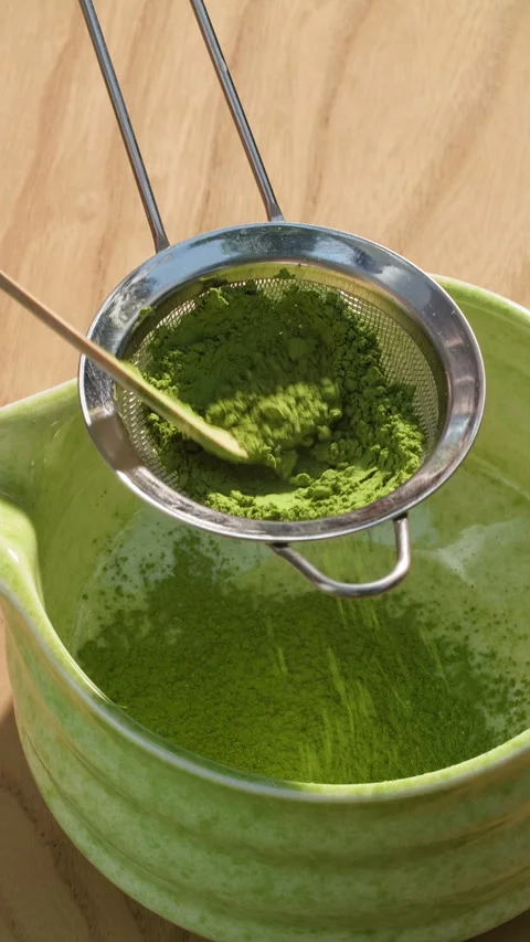 Sifting vibrant green matcha powder through a fine mesh strainer using bamboo Stock-Footage 314005498