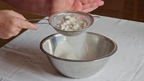 Sifting wheat into a bowl on a table in the kitchen for making a cake, 4k, .. Video stock 241043770