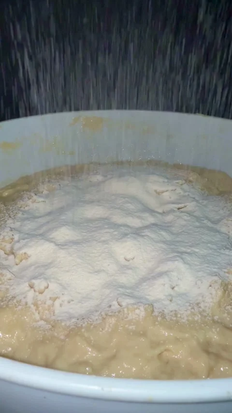 Sifting white flour onto thick dough in a bowl Video stock 334592928