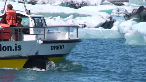 Sightseeing boat sails to the right in front of icebergs at lake Stock Footage 37967594