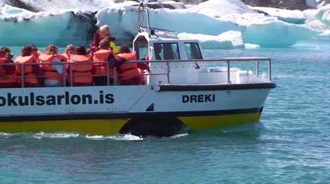 Sightseeing boat sails to the right in front of icebergs at lake Stock Footage 37972427