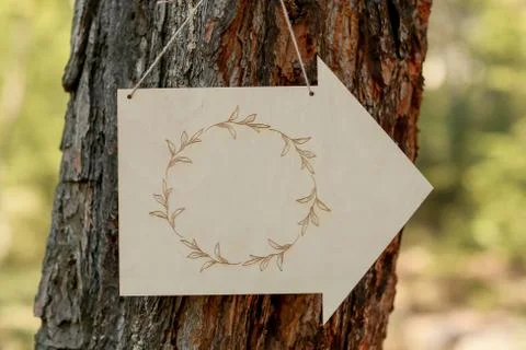 A sign attached to a tree in the shape of an arrow Stock Photos