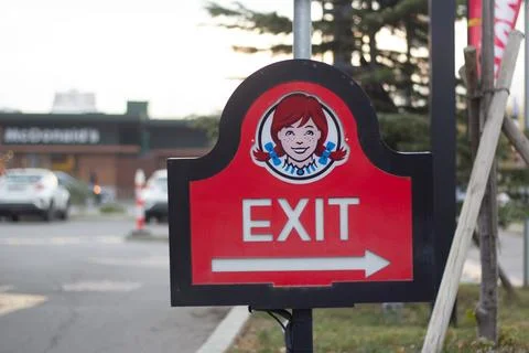 Sign board with text Exit, logo of fast food cafe Wendy's with redhead girl face Stock Photos