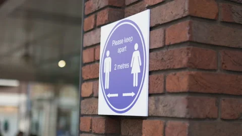 Sign on brick wall requesting people to keep a safe distance Stock Footage 143270727