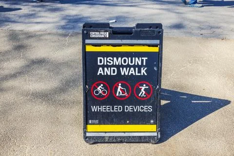 Sign in Central Park instructing visitors to dismount and walk with wheeled Stock Photos