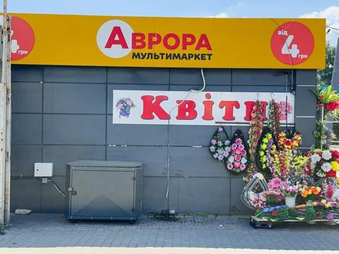 Sign of the cheap store Aurora next to flowers for funeral processions Stock Photos