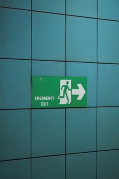 Sign for emergency exit on a tiled wall in a public building Stock Photos