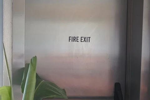 Sign guiding towards the fire exit from inside a building Stock Photos