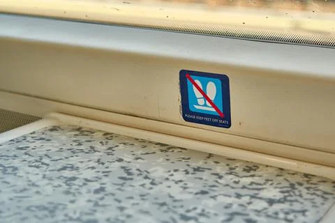 A sign indicating for passengers to keep their feet off of the seats Stock Photos