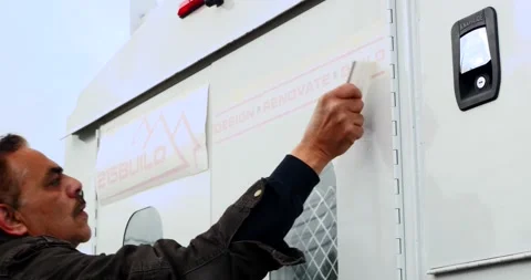 Sign maker applying signage to the back of a truck. Stock Footage 133084714