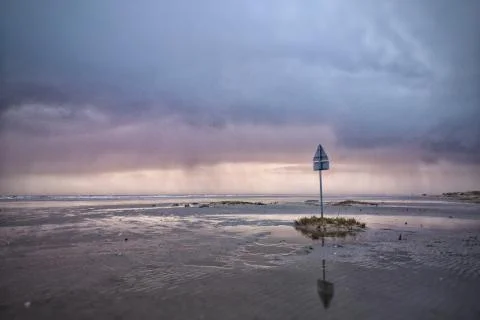 Sign on a metal pole put on the beach under a cloudy sky Foto stock