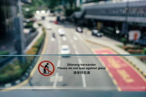 Sign of "please do not lean against glass" on fence of skywalk or flyover Stock Photos