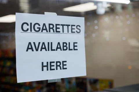 Sign reading CIGARETTES AVAILABLE HERE displayed on glass window of retail .. Stock Photos