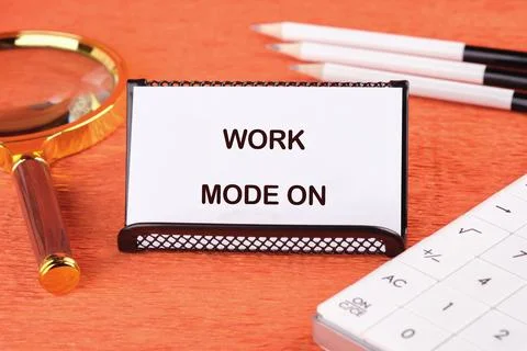 A sign reads WORK MODE ON next to a magnifying glass, pencils, and calculator Stock Photos