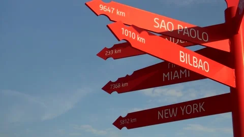 Sign with red arrows pointing at cities around the world Видео 219347080