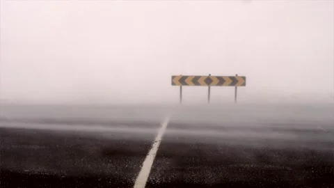 A sign by the road being hammered by a intense snowdrift created by hurricane Stock Footage