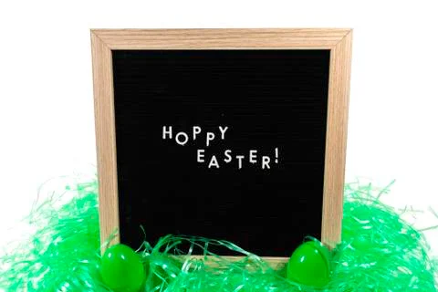 A Sign That Says Happy Easter With Two Green Easter Eggs and Green Easter Gra Stock Photos